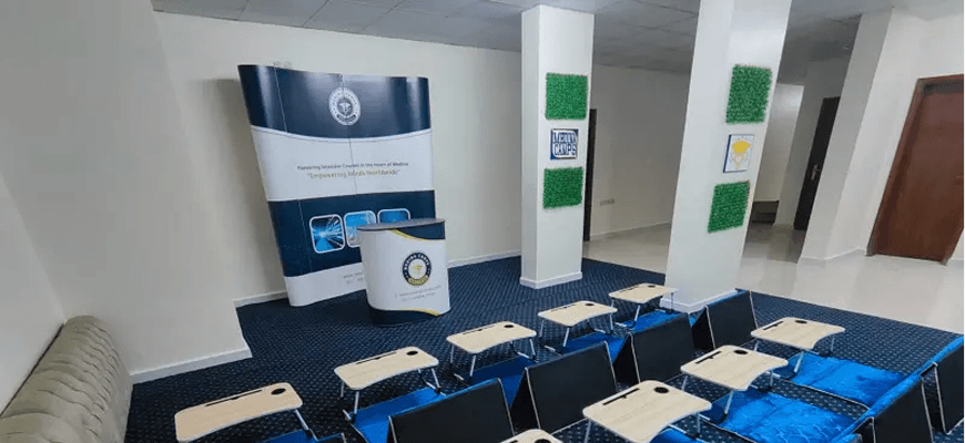Medina Camps seminar room with floor seating, lap desks, and branded backdrop